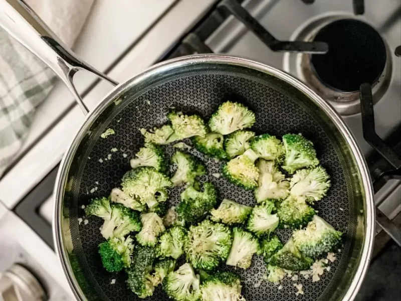 Saltear os brócolos numa frigideira de aço inoxidável em forma de favo de mel